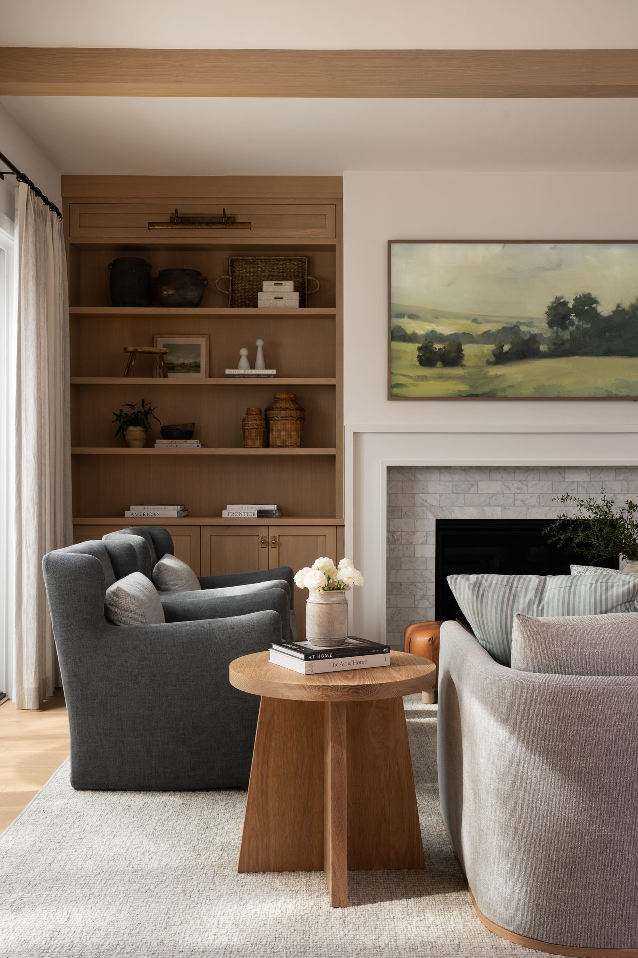 Living room with warm wood built-ins, a fireplace, landscape artwork, and layered lounge seating