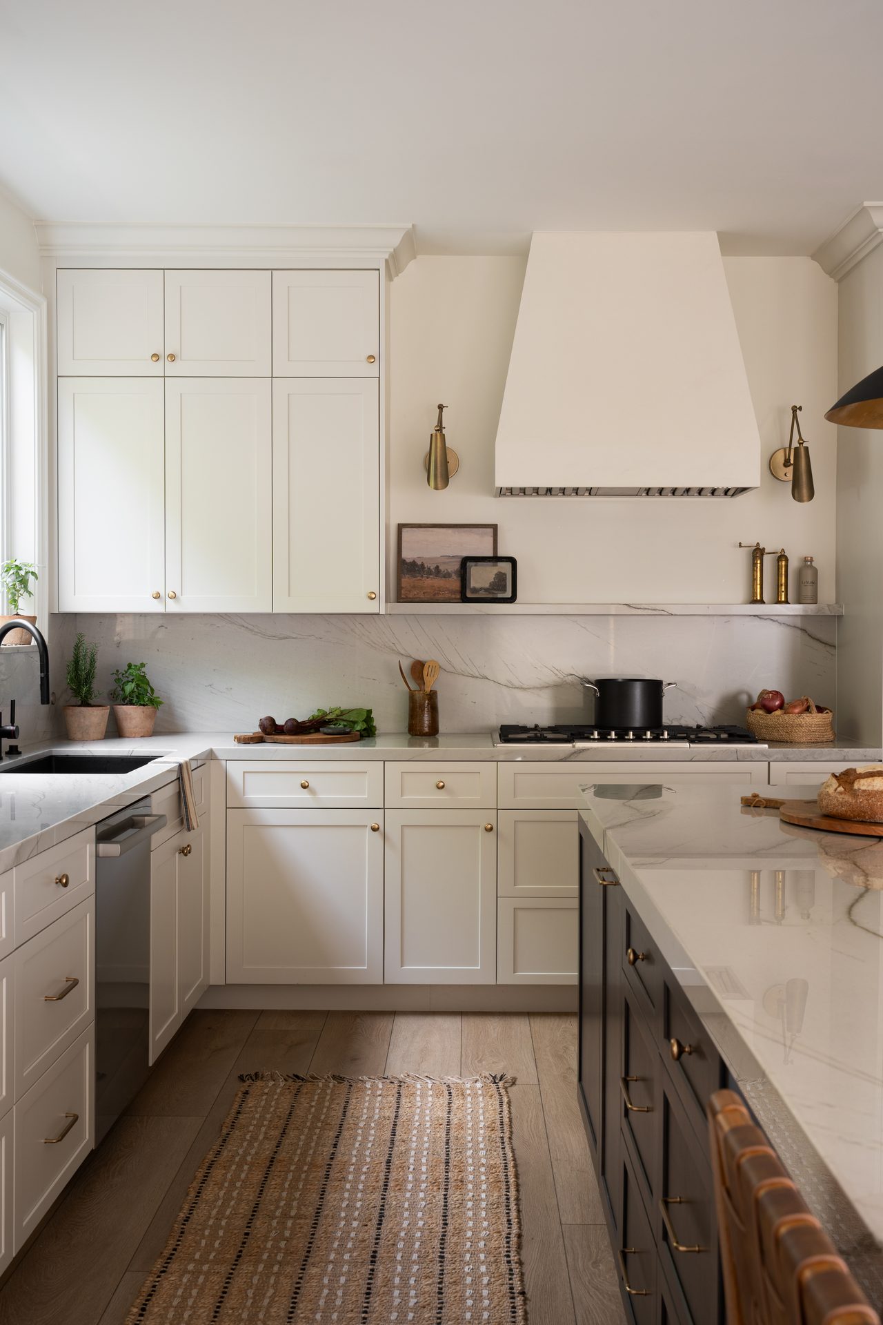 Bright kitchen with cream cabinetry, marble surfaces, brass details, and a warm neutral palette